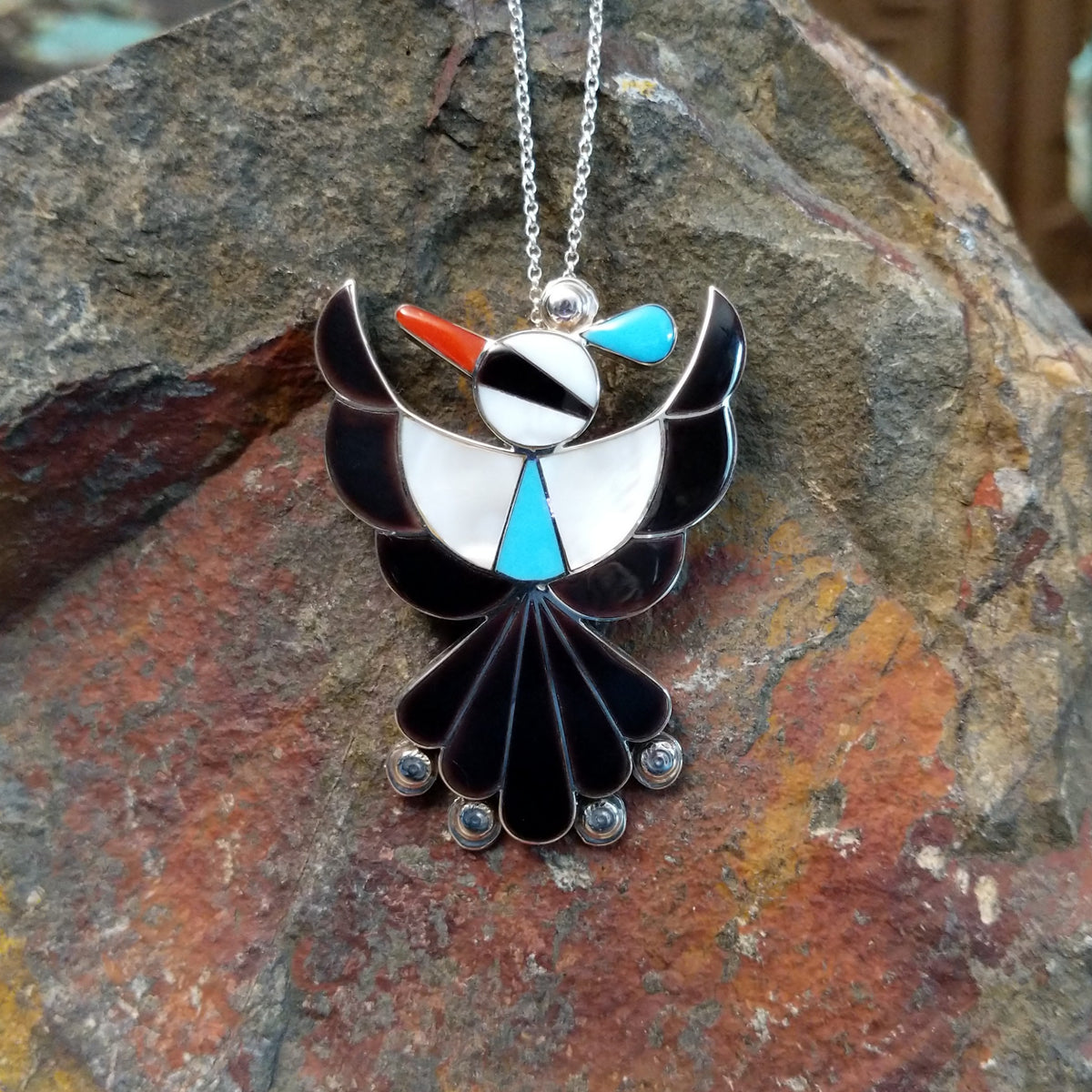 Zuni Thunderbird pendant and pin by Leagus Ahiyite featuring black, white, turquoise, and red stone inlay in a detailed silver Thunderbird design.