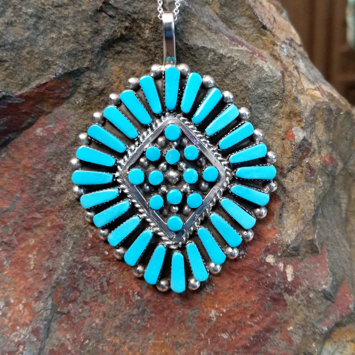 Zuni turquoise cluster pendant by Carlene Hattie featuring tapered and round turquoise stones arranged in an oval cluster with silver bead and twisted-wire detailing.