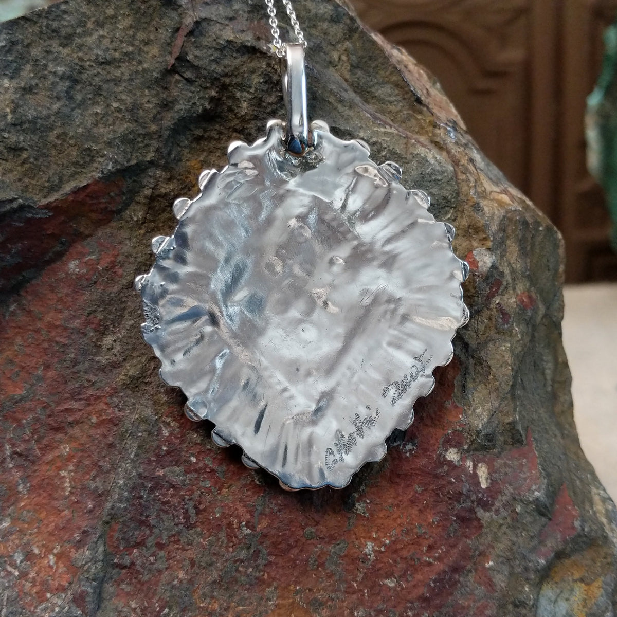 Zuni turquoise cluster pendant by Carlene Hattie featuring tapered and round turquoise stones arranged in an oval cluster with silver bead and twisted-wire detailing; artisan name and tribe.