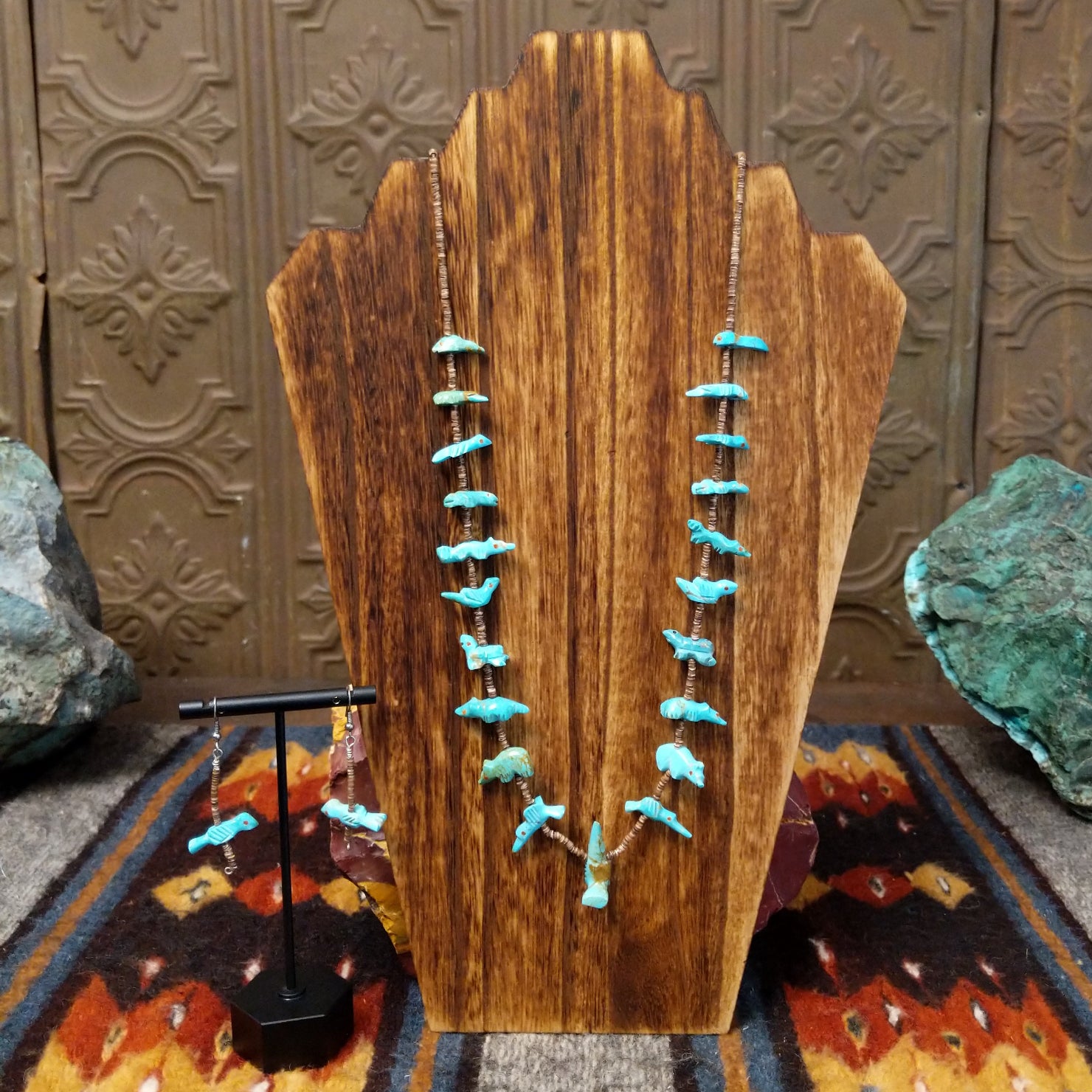 Turquoise fetish heishi necklace and earrings set features a necklace with various turquoise fetish carvings and heishi beads with a sterling silver clasp, paired with matching bird fetish earrings on silver hooks.