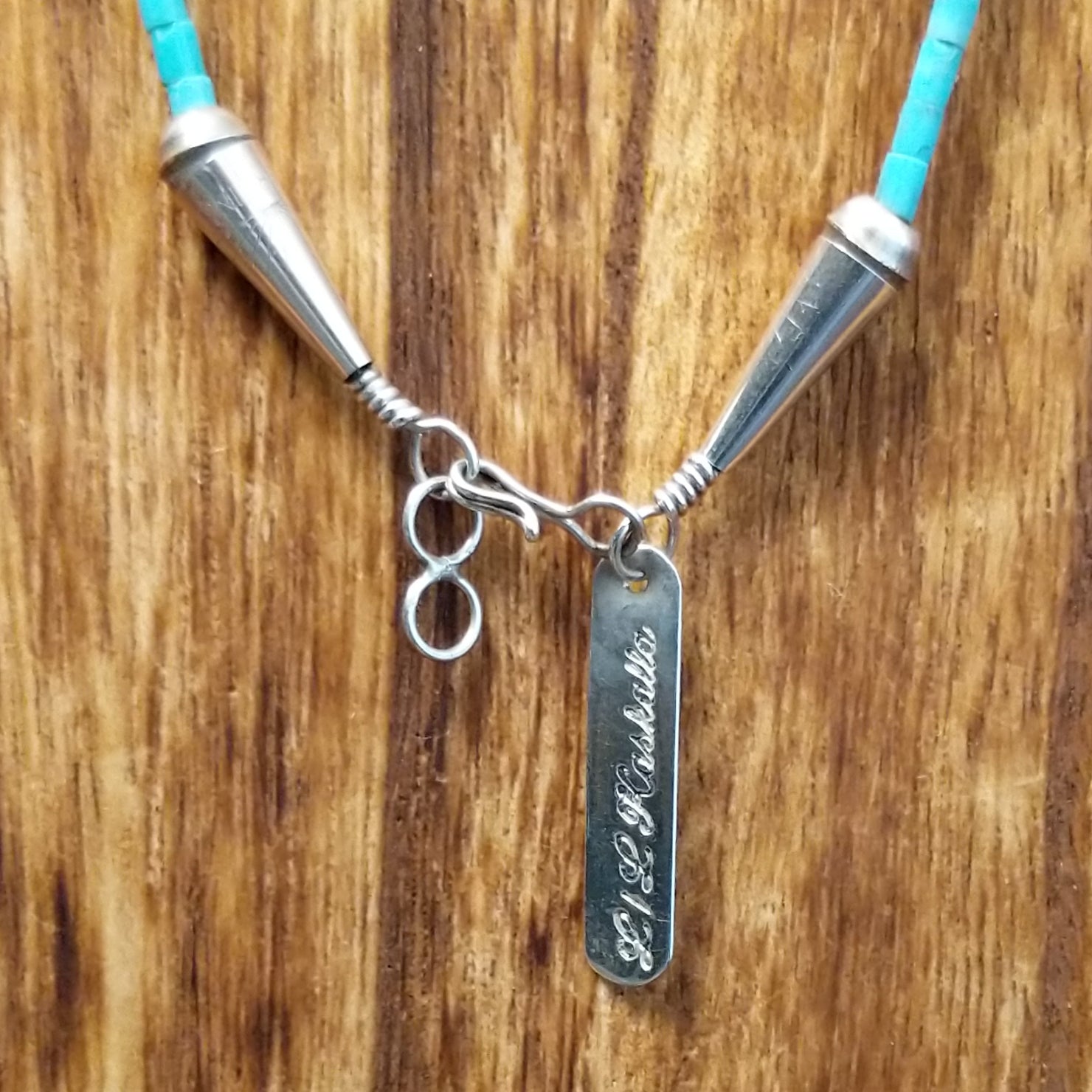 Sterling silver tag and clasp with artist signature etched on the tag.