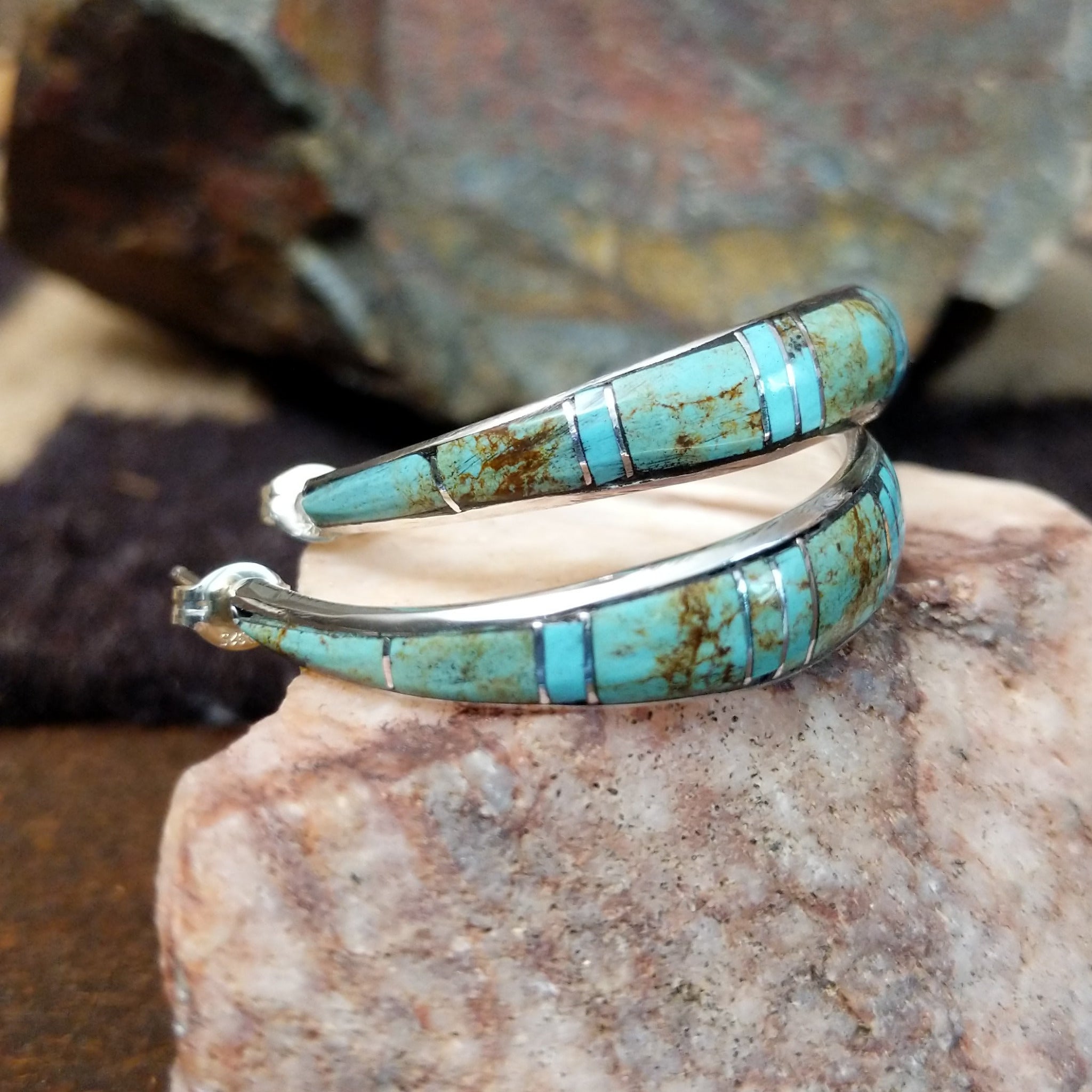 Handcrafted sterling silver Zuni turquoise hoop earrings by Keme Peina, featuring turquoise channel inlay with geometric accents; side view.