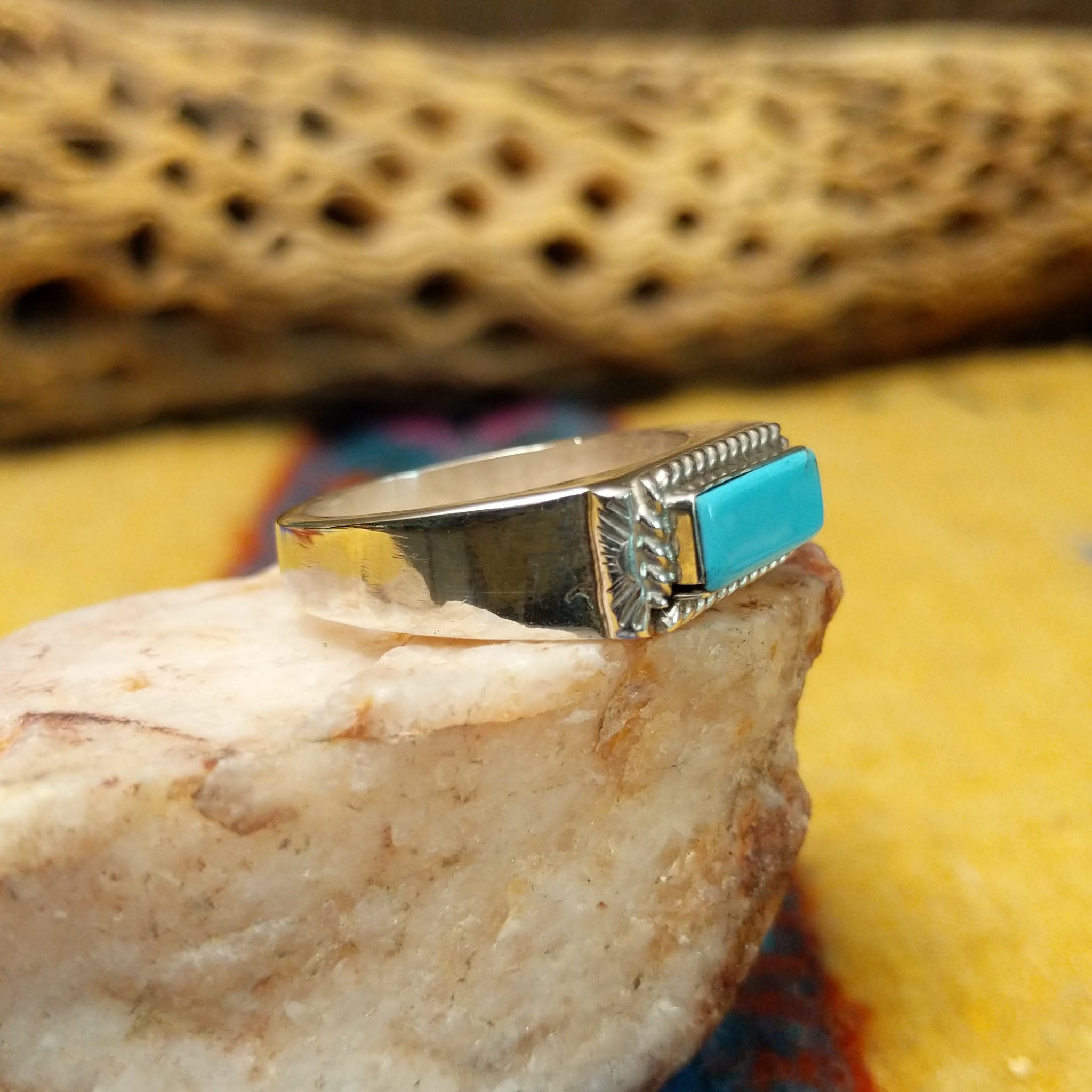Zuni turquoise rectangle ring by A.Q.J., featuring a rectangular turquoise stone with natural blue tones and matrix patterns set in a handcrafted sterling silver band. Side view.