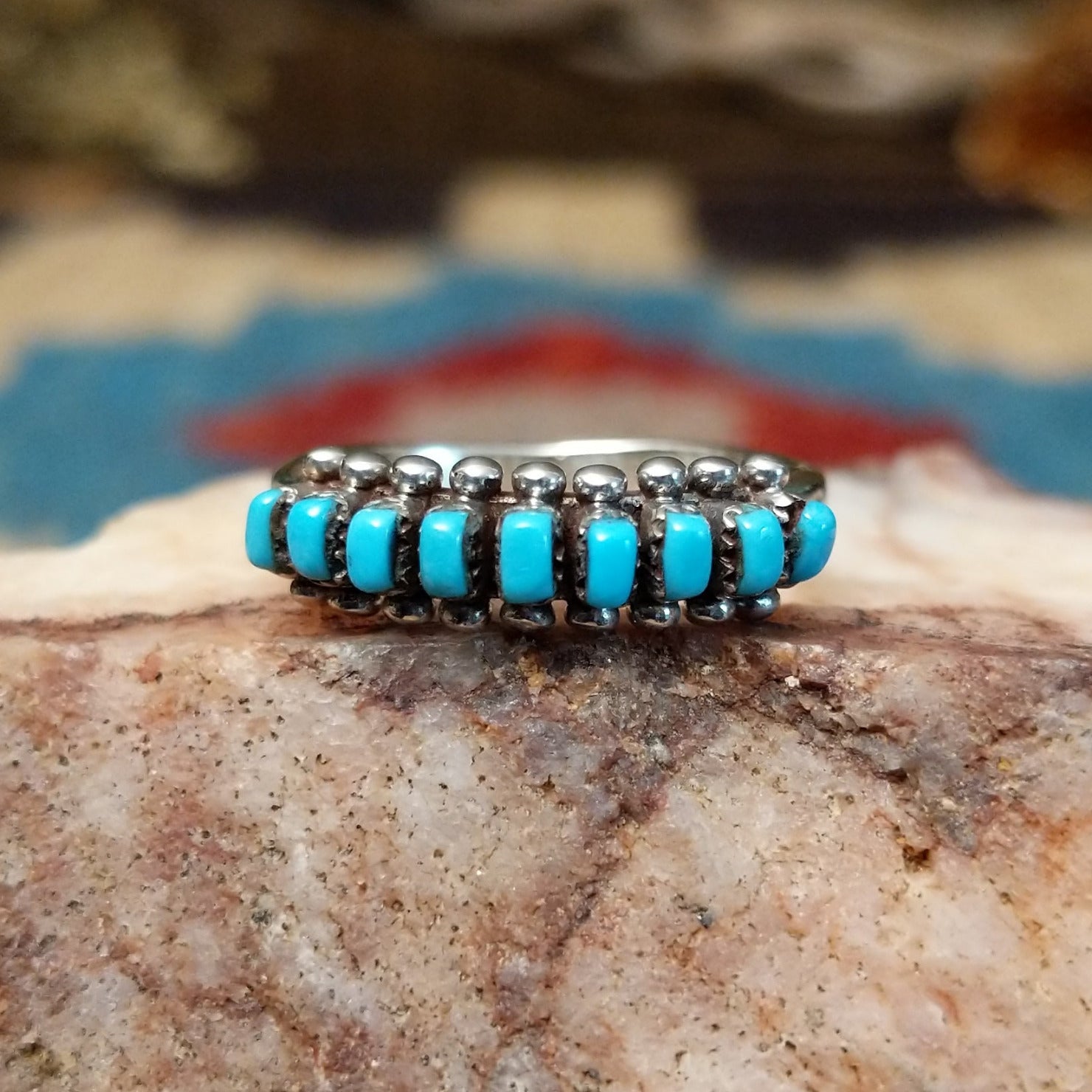 Sterling silver ring with turquoise set in notched bezels, arranged in rows with dotted accents.