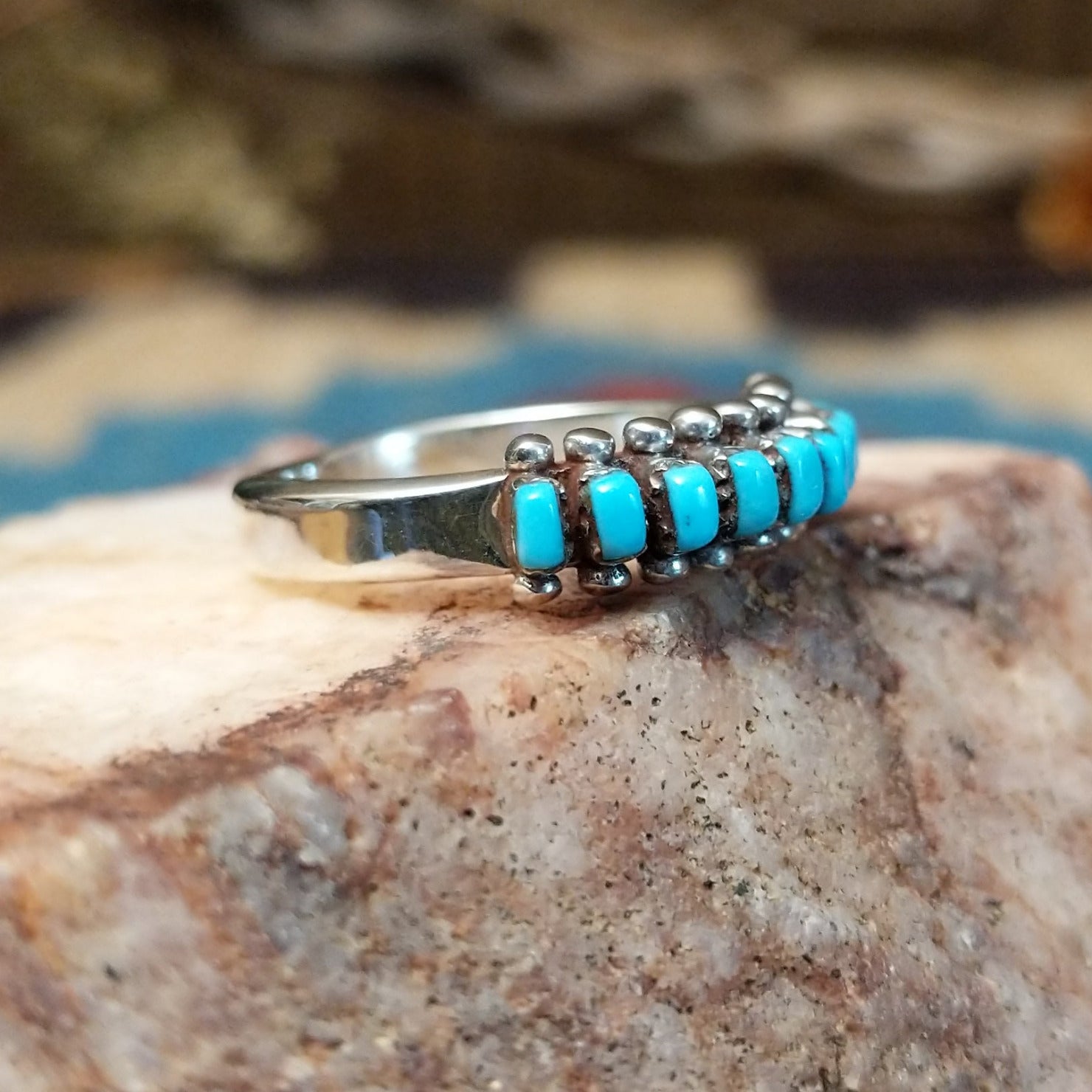 Sterling silver ring with turquoise set in notched bezels, arranged in rows with dotted accents.