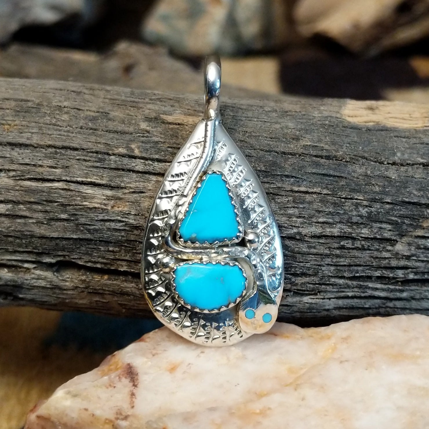 Sterling silver pendant with turquoise set in the bezel, framed by the hammered finish of the silver and snake design.