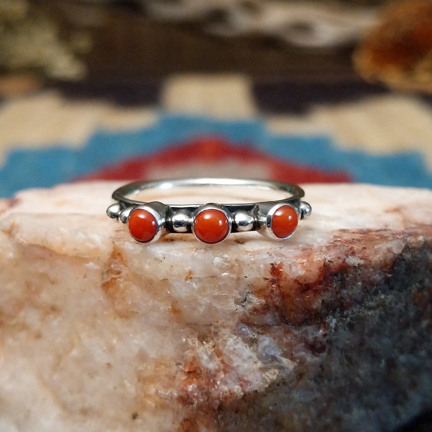 Sterling silver ring with coral set in three small, round bezels.