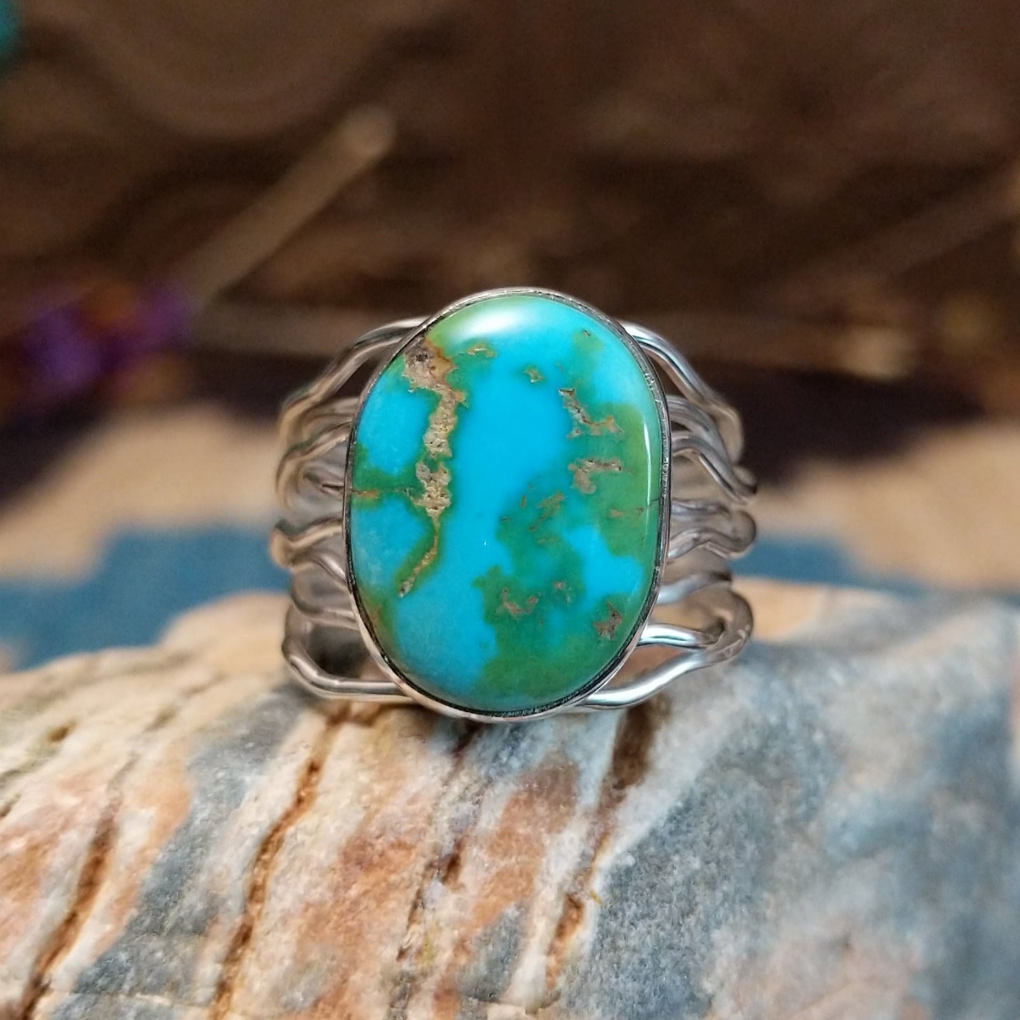 Sterling silver ring with Sonoran gold turquoise set in an oval bezel and band with strands of silver.