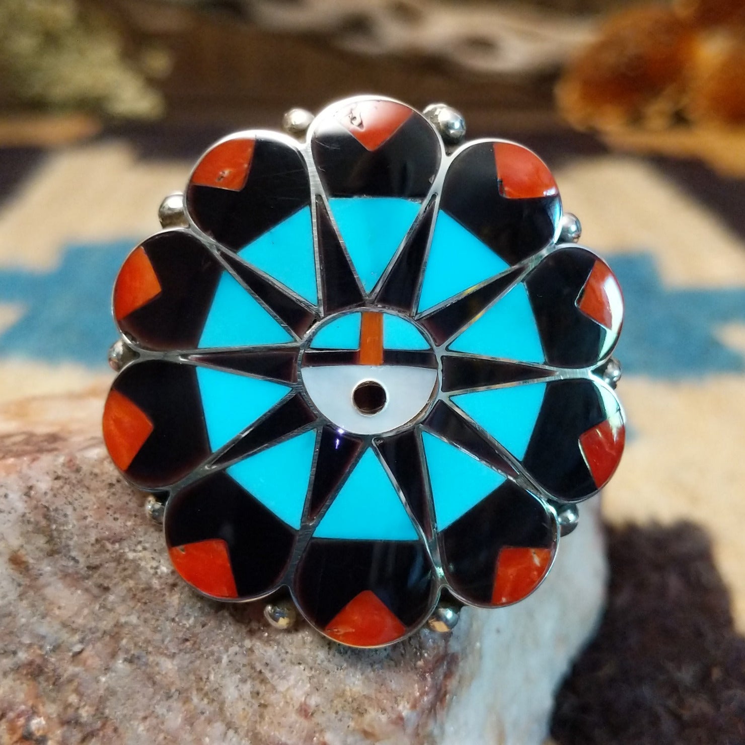 Sterling silver ring with multistone inlay creating a sunface motif.