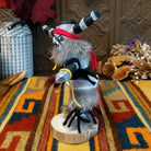 Side view of the Navajo Clown Kachina doll with black-and-silver striped horns, smiling painted face, gray fur, striped body, and red fabric apron.