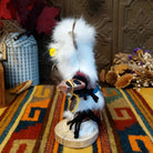 Side view of the Navajo Owl Kachina doll with fluffy white fur, black eyes, yellow-trimmed beak, brown feathers around the head, and blue belt.