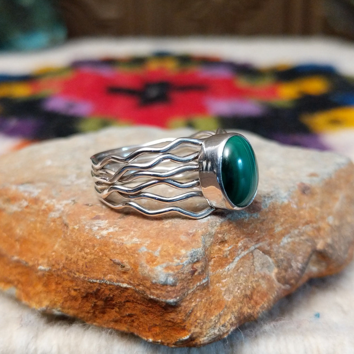 Malachite ring by Angela Martin with an oval banded stone and multi-strand wavy silver band.