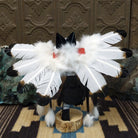 Navajo-made eagle kachina doll by M. C. with white feathered wings, blue mask, yellow beak, and black garments.