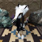 Navajo-made eagle kachina doll by M. C. with white feathered wings, blue mask, yellow beak, and black garments.