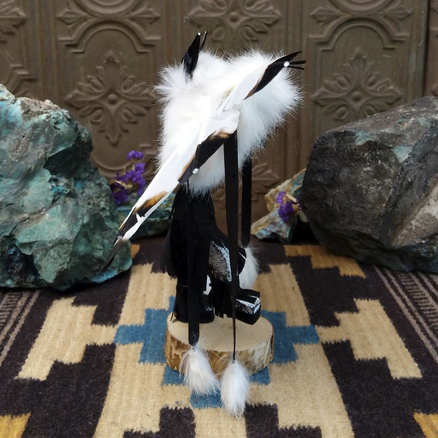 Navajo-made eagle kachina doll by M. C. with white feathered wings, blue mask, yellow beak, and black garments.