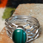 Malachite ring by Angela Martin with an oval banded stone and multi-strand wavy silver band. Close up of the artist's stamped signature. 