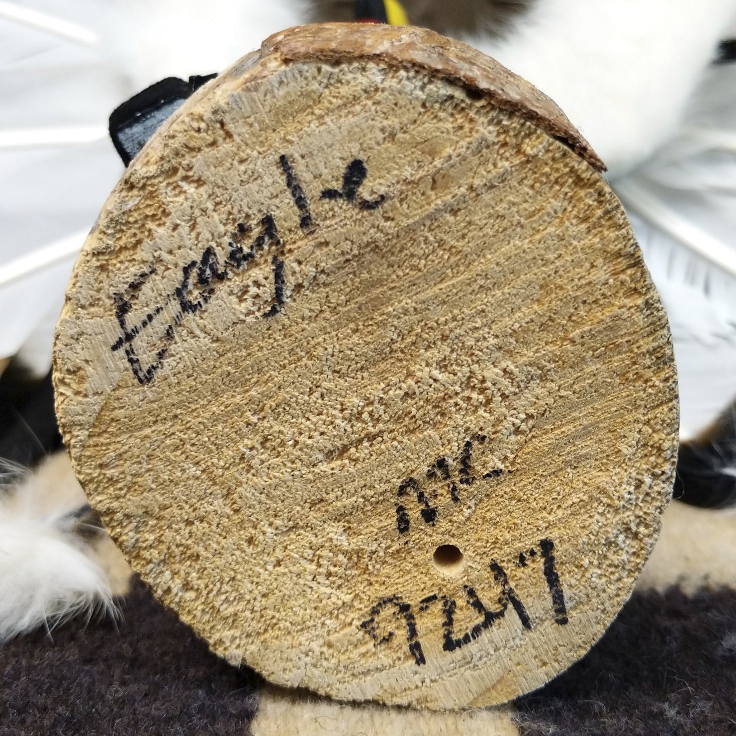 Underside of M. C. eagle dancer kachina doll showing handwritten signature and label on wood base.
