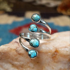 Sterling silver ring with #8 turquoise set in individual, round bezels suspended on strands of silver.