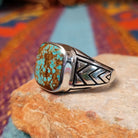 #8 Turquoise Ring by Terry Wood featuring a square turquoise stone with prominent natural brown matrix, set in Sterling Silver with geometric openwork detailing along the band; side view.