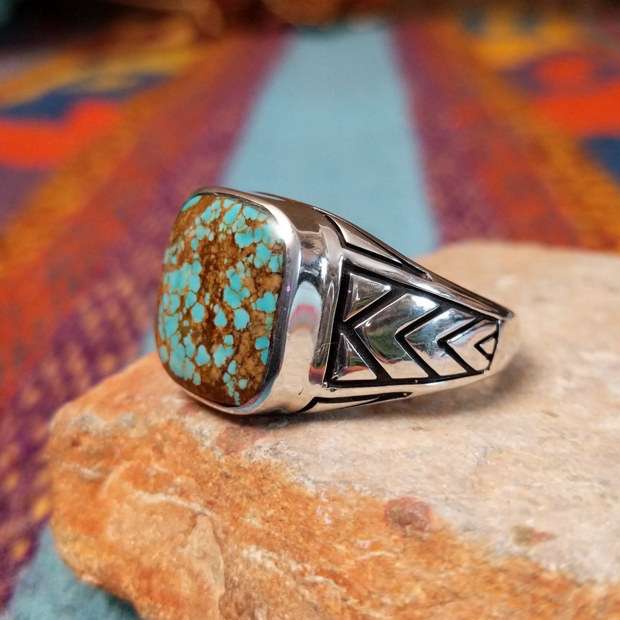 #8 Turquoise Ring by Terry Wood featuring a square turquoise stone with prominent natural brown matrix, set in Sterling Silver with geometric openwork detailing along the band; side view.