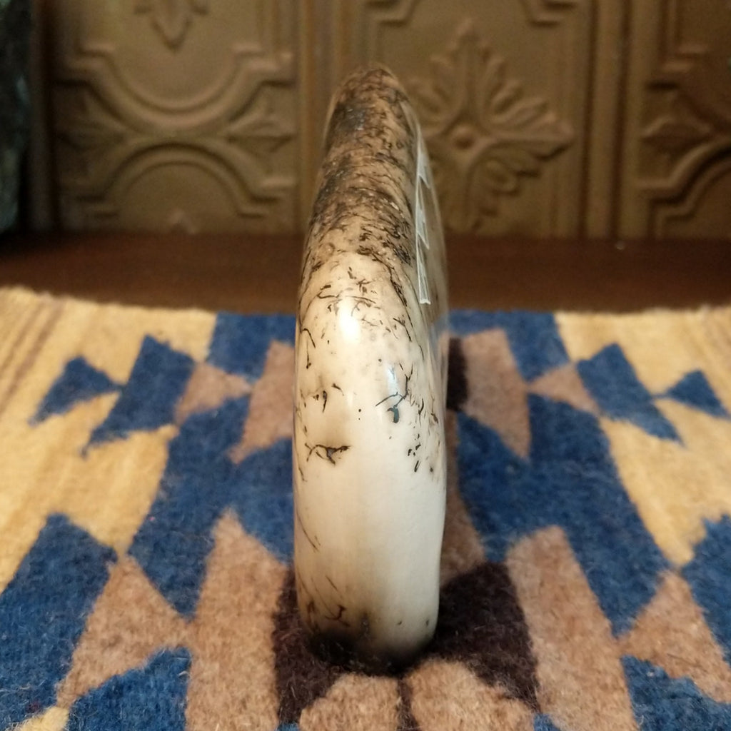 White clay molded into a bison figure with fired horsehair along its body and unique etched patterns on its body.