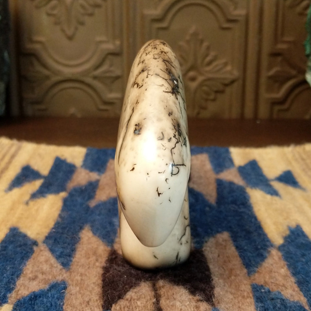 White clay molded into a bison figure with fired horsehair along its body and unique etched patterns on its body.