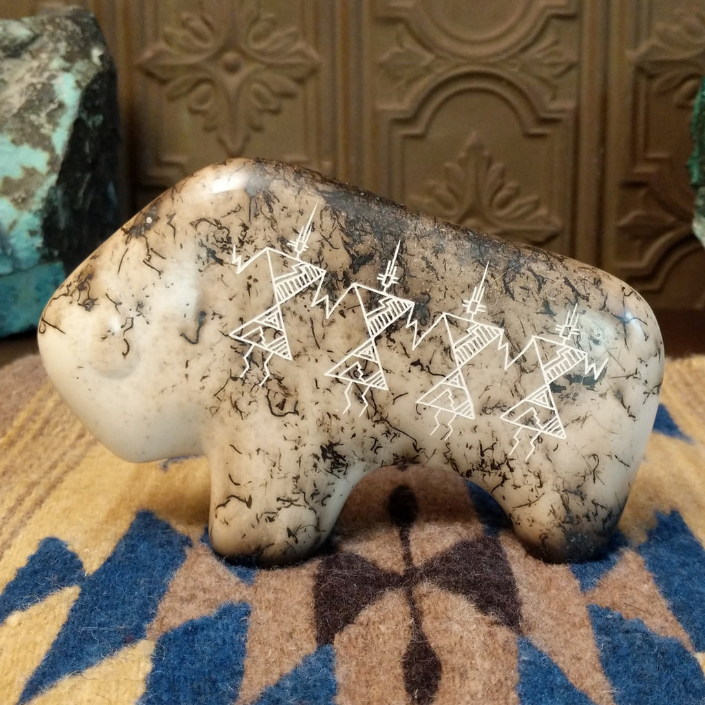 White clay molded into a bison figure with fired horsehair along its body and unique etched patterns on its body.