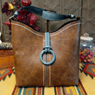Alexa Handbag by Liz Soto featuring a tall structured silhouette, decorative contrast stitching, vertical center detailing, large wrapped circular accent, and wide shoulder strap.