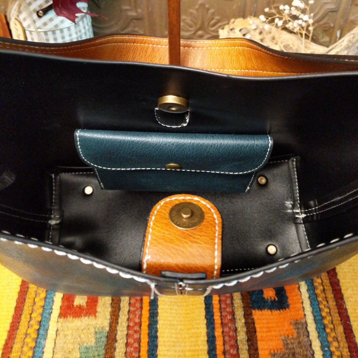 Alexa Handbag by Liz Soto featuring a tall structured silhouette, decorative contrast stitching, vertical center detailing, large wrapped circular accent, and wide shoulder strap.