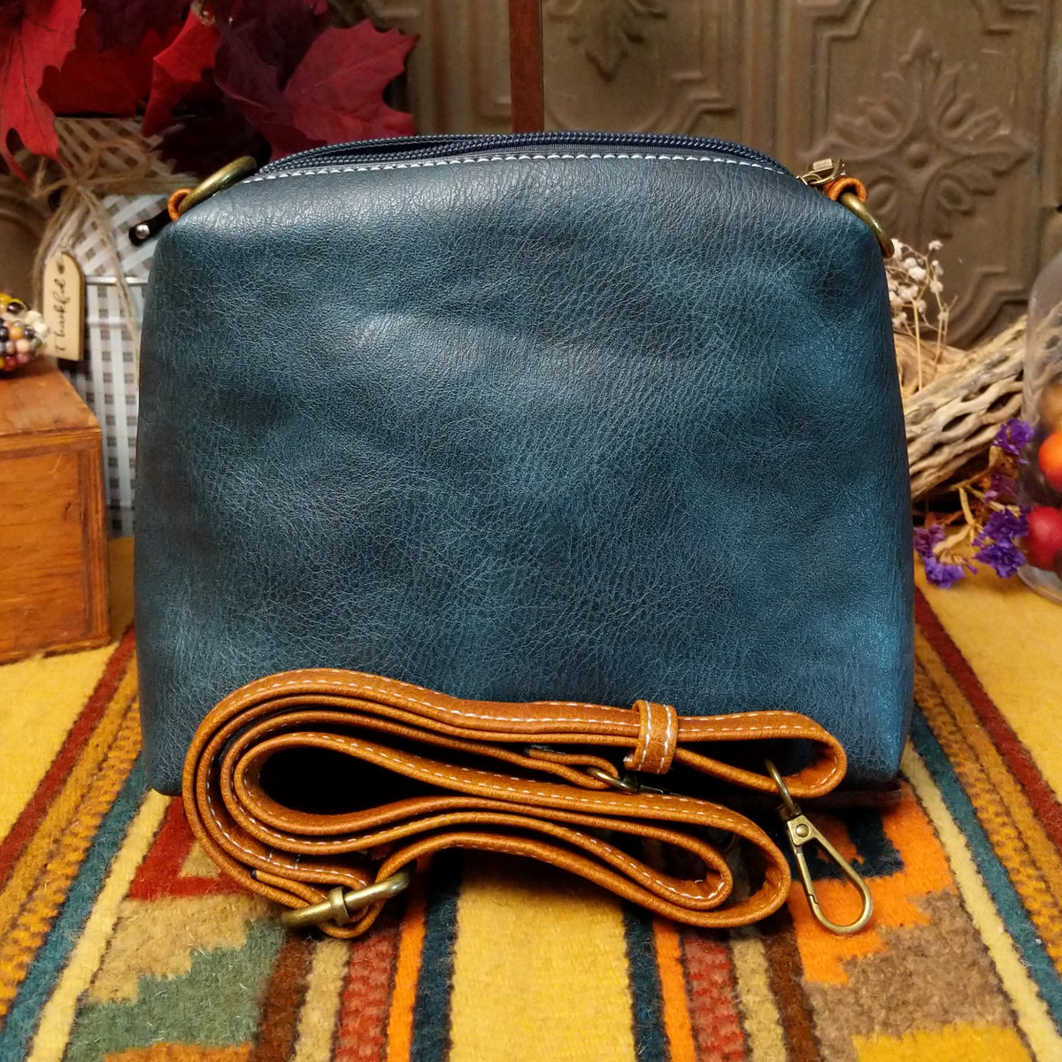 Alexa Handbag by Liz Soto featuring a tall structured silhouette, decorative contrast stitching, vertical center detailing, large wrapped circular accent, and wide shoulder strap.