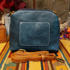 Alexa Handbag by Liz Soto featuring a tall structured silhouette, decorative contrast stitching, vertical center detailing, large wrapped circular accent, and wide shoulder strap.