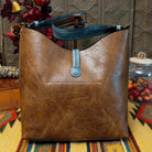 Alexa Handbag by Liz Soto featuring a tall structured silhouette, decorative contrast stitching, vertical center detailing, large wrapped circular accent, and wide shoulder strap; back.