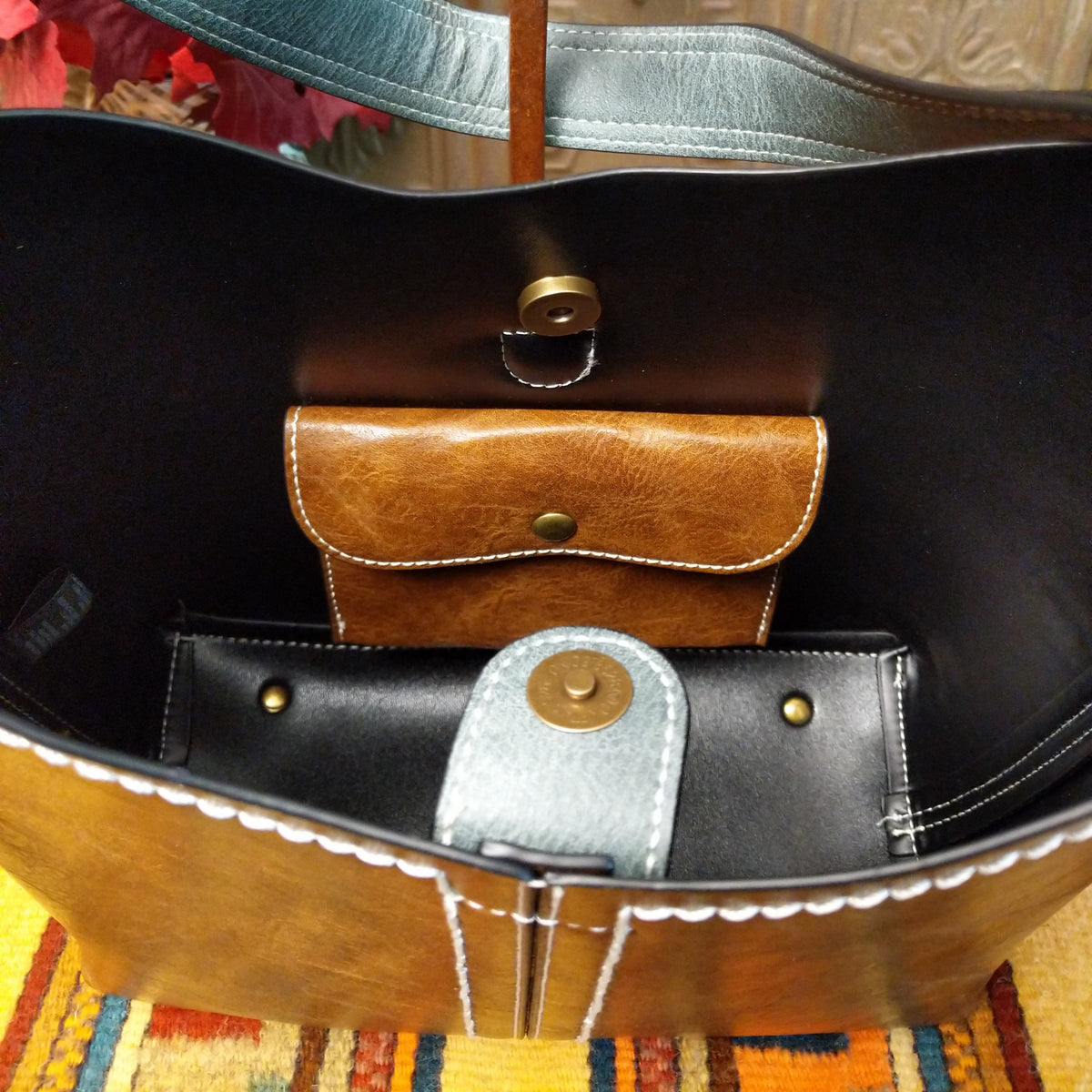 Alexa Handbag by Liz Soto featuring a tall structured silhouette, decorative contrast stitching, vertical center detailing, large wrapped circular accent, and wide shoulder strap; interior.