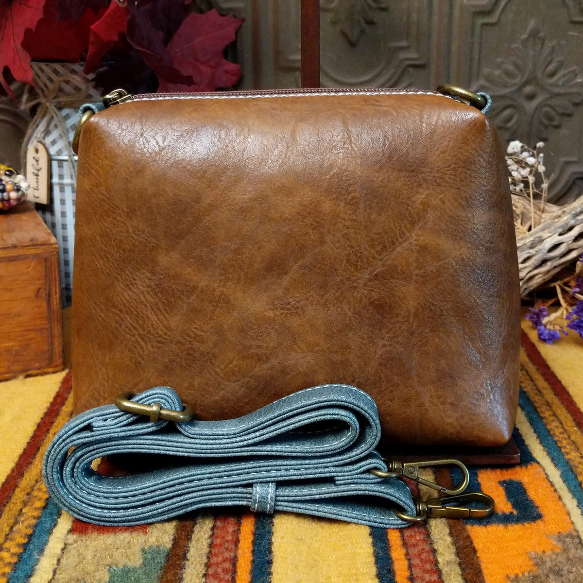 Alexa Handbag by Liz Soto featuring a tall structured silhouette, decorative contrast stitching, vertical center detailing, large wrapped circular accent, and wide shoulder strap.