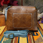 Alexa Handbag by Liz Soto featuring a tall structured silhouette, decorative contrast stitching, vertical center detailing, large wrapped circular accent, and wide shoulder strap.