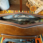 Alexa Handbag by Liz Soto featuring a tall structured silhouette, decorative contrast stitching, vertical center detailing, large wrapped circular accent, and wide shoulder strap; interior.
