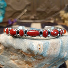 Sterling silver cuff with coral set in notched bezels that alternate across the surface of the band.