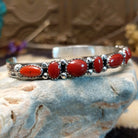 Sterling silver cuff with coral set in notched bezels that alternate across the surface of the band.