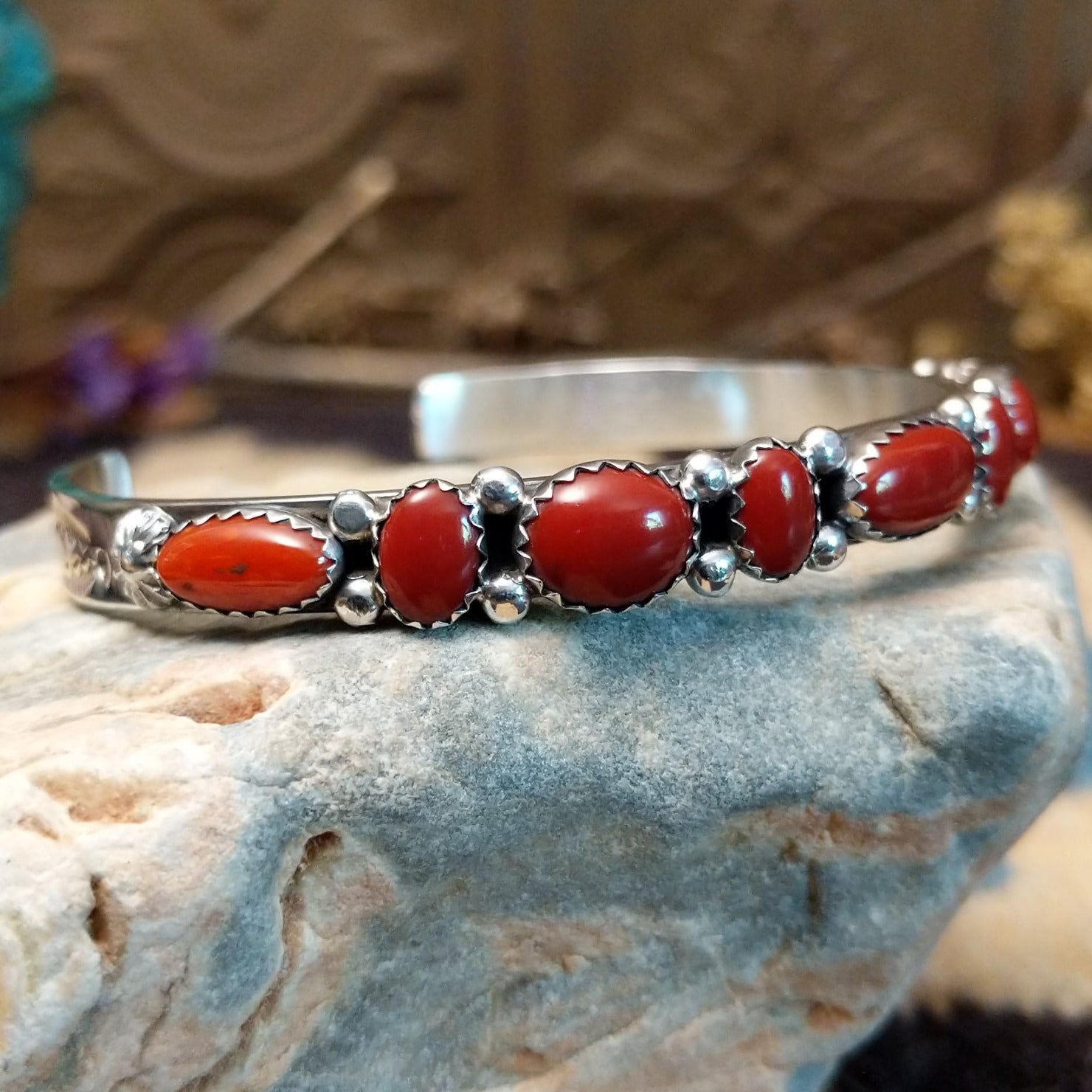 Sterling silver cuff with coral set in notched bezels that alternate across the surface of the band.