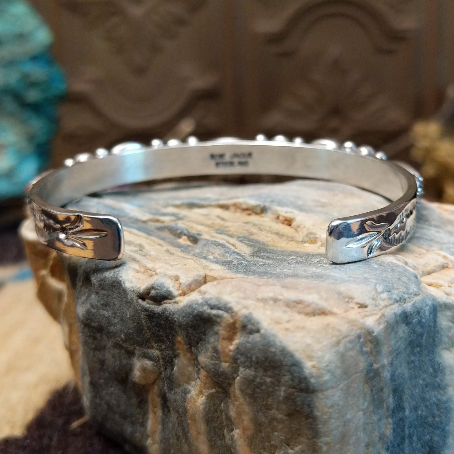Sterling silver cuff with coral set in notched bezels that alternate across the surface of the band.