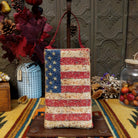 Americana Club Bag by Bamboo Trading featuring a sparkling American flag design with red and cream beaded stripes, gold stars on a textured blue background, and a coordinating red shoulder strap.