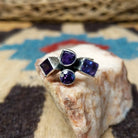 Amethyst ring by Ann Curley, featuring four faceted purple amethyst gemstones in round, square, rectangular, and pear shapes set in a handcrafted sterling silver ring.