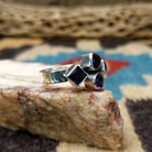 Amethyst ring by Ann Curley, featuring four faceted purple amethyst gemstones in round, square, rectangular, and pear shapes set in a handcrafted sterling silver ring.  Side view.