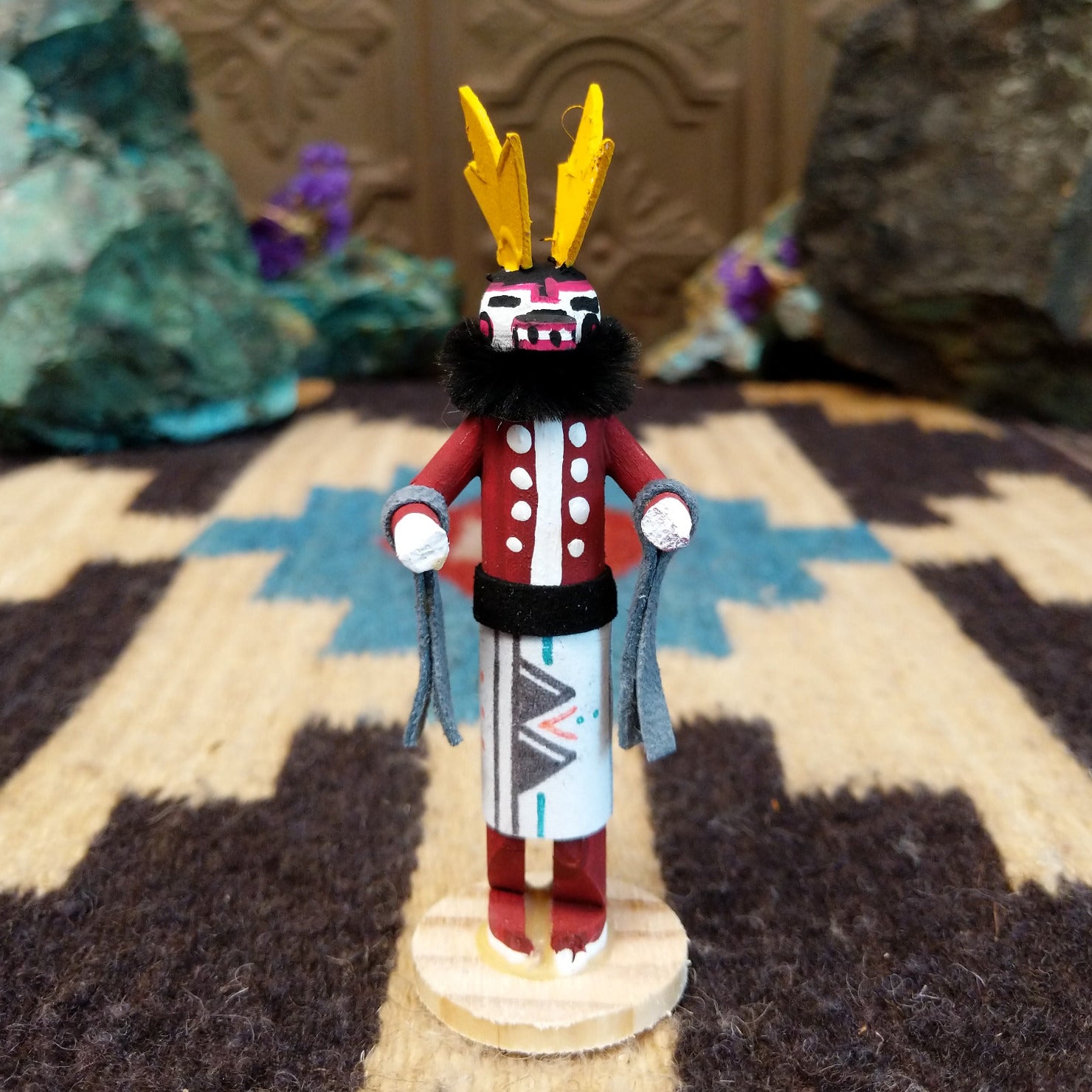 Mini antelope kachina by Rosalind Grey with yellow horns, red body, black fur collar, and white geometric-patterned garment.