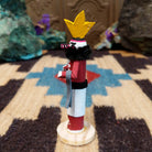 Mini antelope kachina by Rosalind Grey with yellow horns, red body, black fur collar, and white geometric-patterned garment.