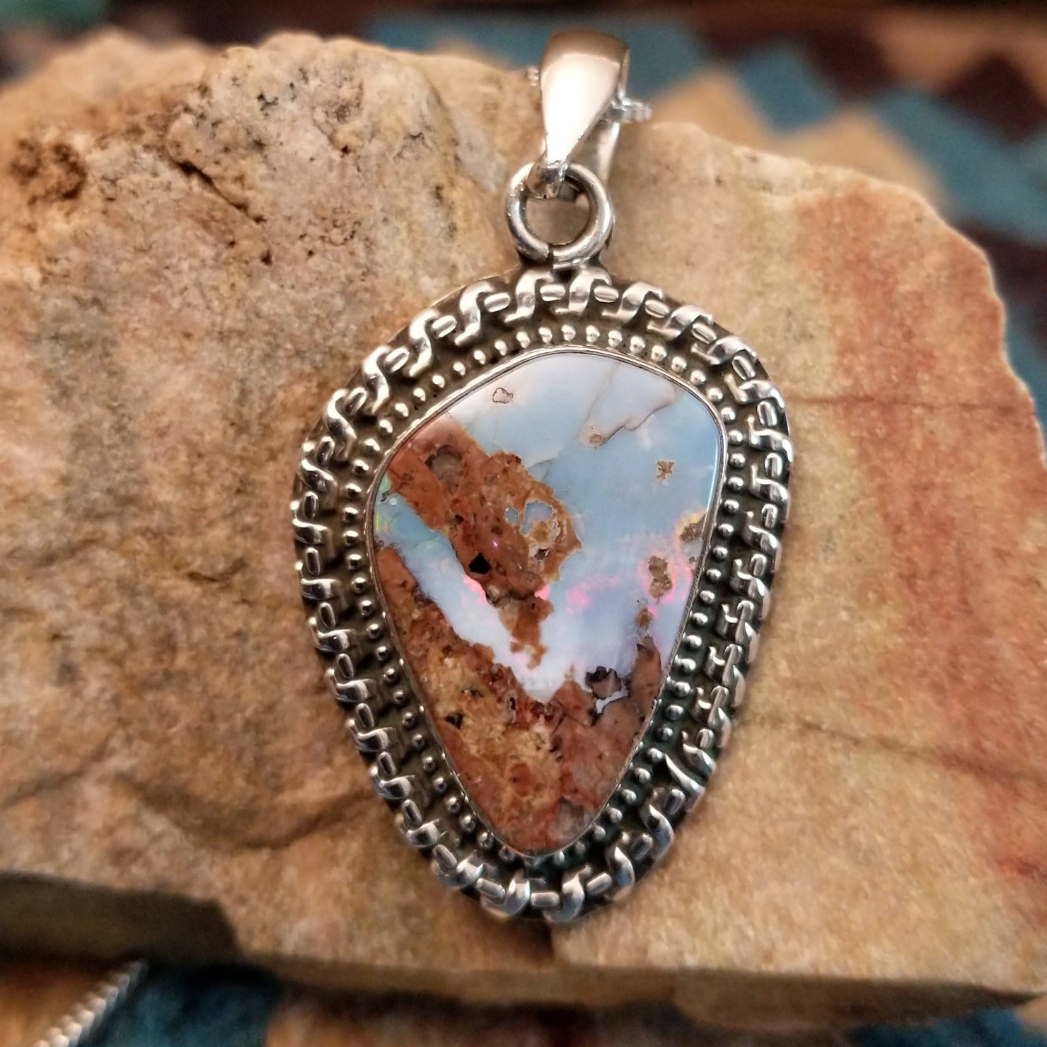 Sterling silver pendant with Arizona blue opal set in the bezel, framed by ornate silverwork.