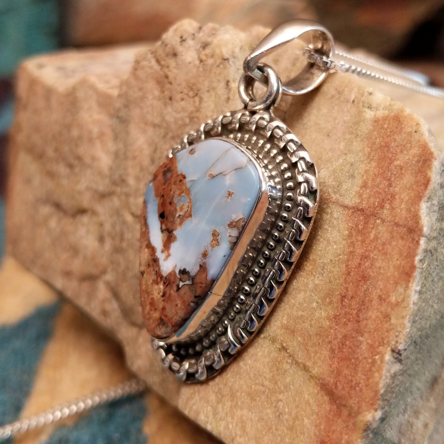 Sterling silver pendant with Arizona blue opal set in the bezel, framed by ornate silverwork.