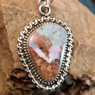 Sterling silver pendant with Arizona blue opal set in the bezel, framed by ornate silverwork.