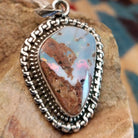 Sterling silver pendant with Arizona blue opal set in the bezel, framed by ornate silverwork.