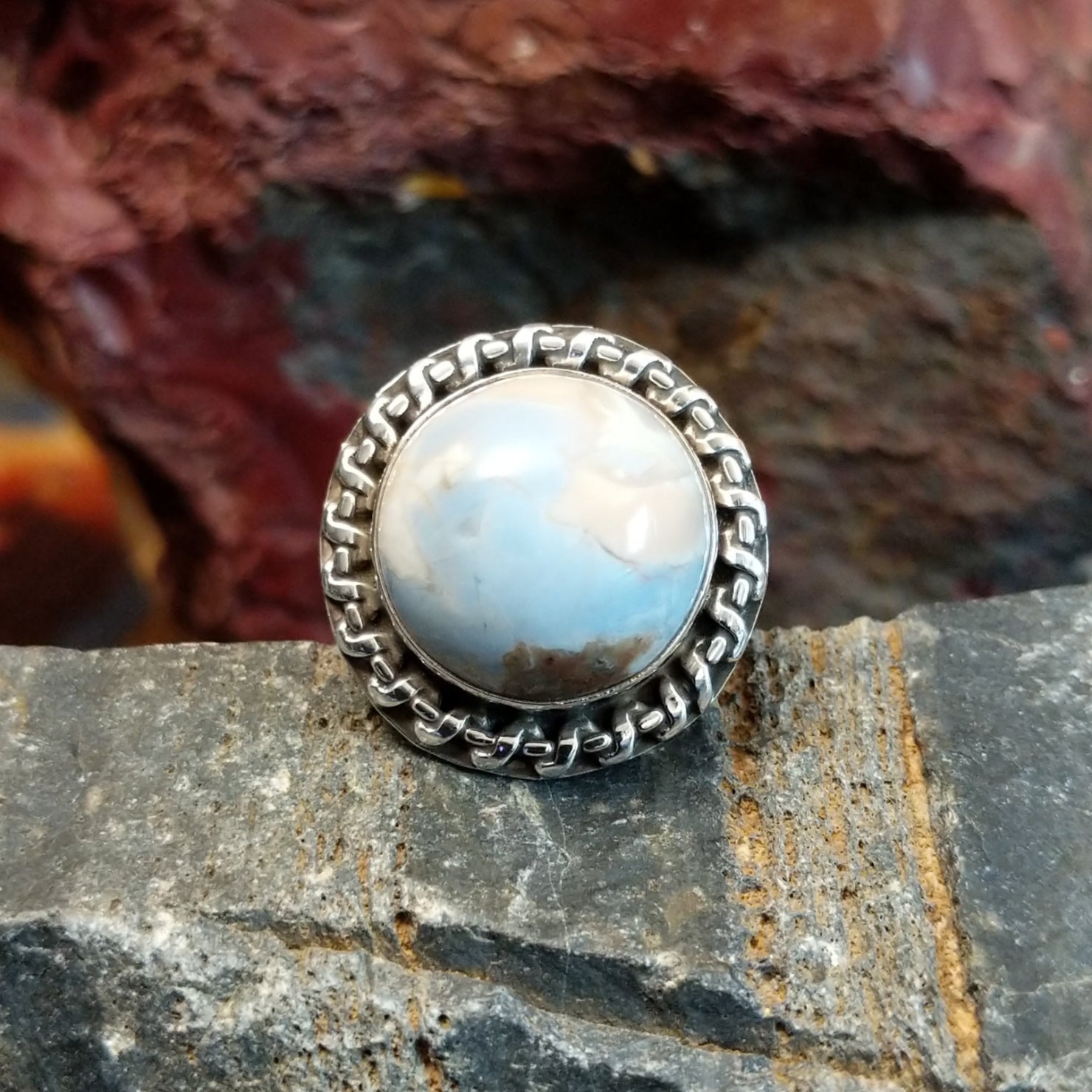 Ring features a large, dome-shaped blue opal set in a twisted silver band.